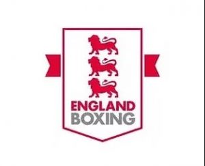 The England Boxing logo featuring three red lions stacked above the words ENGLAND BOXING in red and grey text, with a red ribbon extending from both sides of the white shield-shaped emblem.